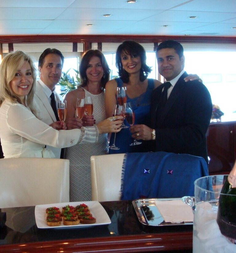 Jan Wallace, James Bianco, Sue Masterson, Afshan, and Amin Lahka — champagne toast aboard a yacht